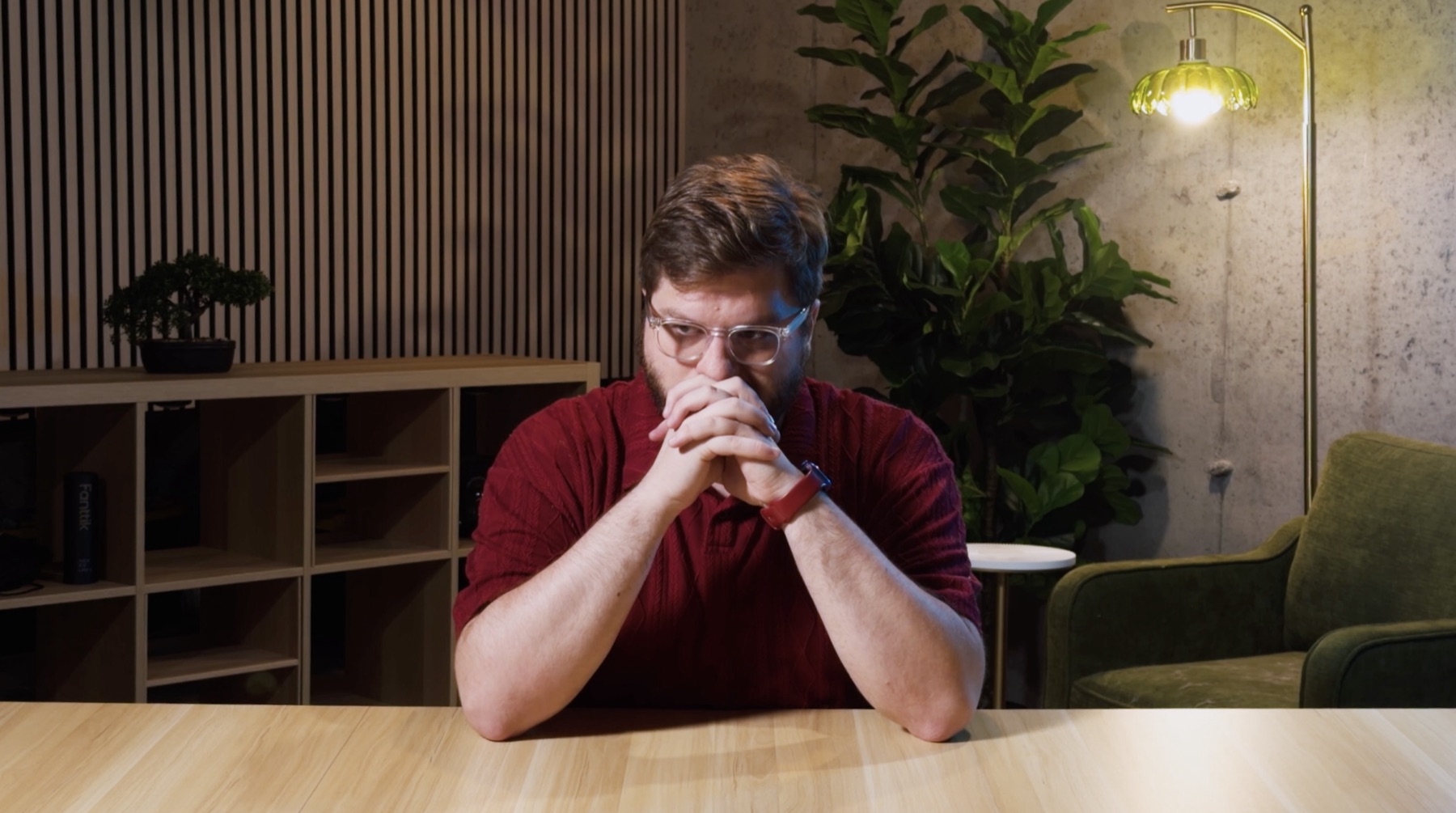 Joshua Keith with his hands clasped in front of his face, in his studio